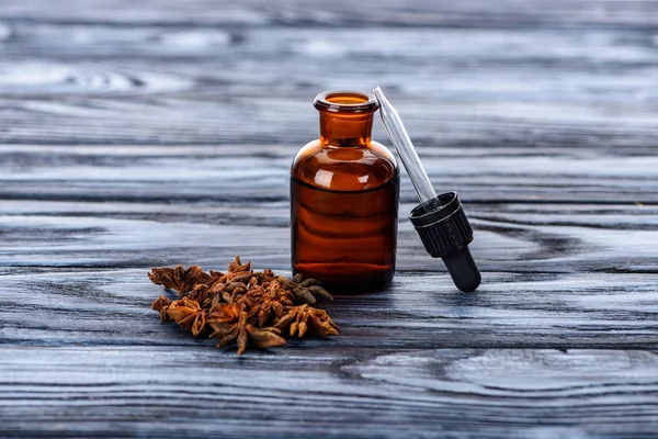 Botella de aceite esencial de hierbas naturales, gotero y clavel en la superficie gris - foto de stock