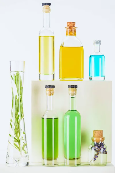 Бутылки цветных натуральных растительных эфирных масел на белой поверхности — стоковое фото