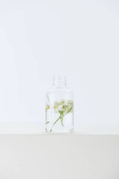 Bottle of natural herbal essential oil with chamomile flowers on white surface — Stock Photo