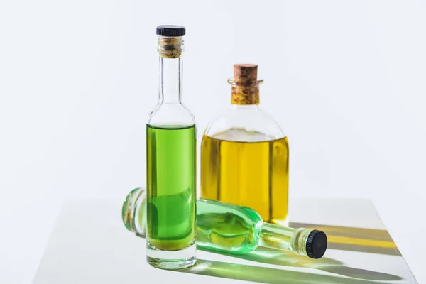 Бутылки натуральных травяных эфирных зеленых и желтых масел на белом кубе — стоковое фото