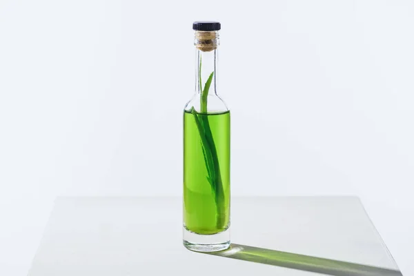 Bottiglia di olio essenziale verde naturale alle erbe con aloe vera su cubo bianco — Foto stock