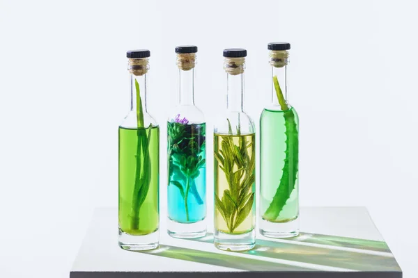 Quatro garrafas de óleos naturais de ervas essenciais coloridos em cubo branco — Fotografia de Stock