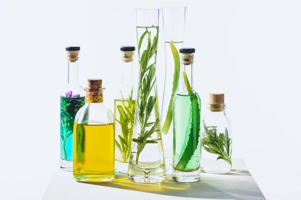 Frascos de aceites verdes y amarillos esenciales aromáticos orgánicos sobre cubo blanco - foto de stock