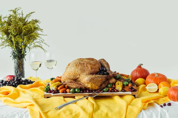 Vista de cerca de la cena de acción de gracias festiva conjunto de mesa con copas de vino, pavo asado y verduras en la mesa con mantel - foto de stock