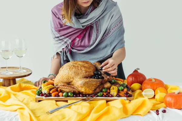Частичный вид женщины и жареной индейки с овощами на праздничный ужин на сером фоне — стоковое фото