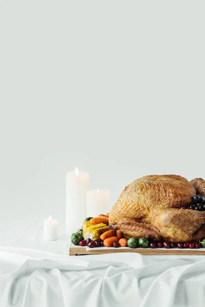 Primer plano vista de velas arregladas, pavo festivo con verduras asadas para la cena de vacaciones en la mesa sobre fondo gris, concepto de fiesta de acción de gracias - foto de stock