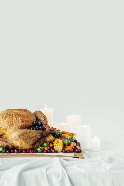 Vista de perto das velas arranjadas, peru festivo com legumes assados para o jantar de férias na mesa em pano de fundo cinza, conceito de feriado de ação de graças — Stock Photo