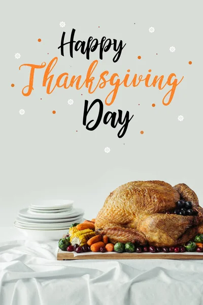 Close up view of roasted turkey, cutlery and happy thanksgiving day lettering on grey background — Stock Photo