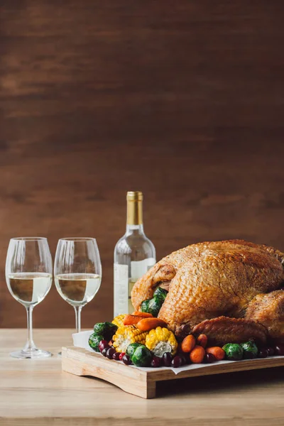 Close up view of traditional roasted turkey, vegetables and glasses of wine for thanksgiving dinner on wooden tabletop — Stock Photo