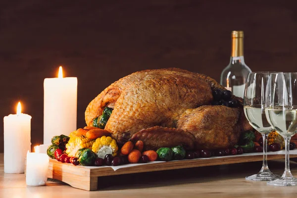 Nahaufnahme von Kerzen, traditionell gebratenem Truthahn, Gemüse und Weingläsern zum Erntedank auf einer Holzplatte — Stockfoto