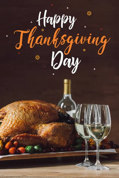 Close up view of roasted turkey, glasses of wine and happy thanksgiving day lettering — Stock Photo