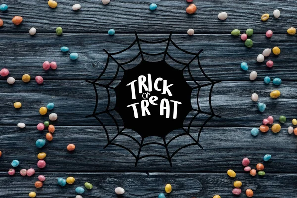 Підвищений вигляд розставлених барвистих смачних цукерок на дерев'яному фоні з павутинною павутиною та написанням — стокове фото