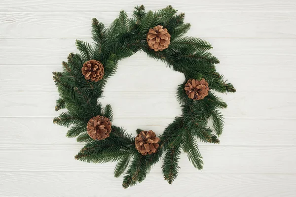 Close-up view of beautiful christmas wreath with pine cones on white wooden background — Stock Photo