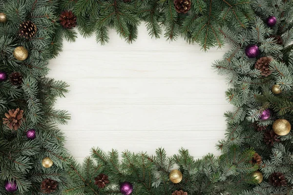 Vista dall'alto di bellissimi ramoscelli di abete sempreverde con palline lucide e pigne su sfondo bianco in legno — Foto stock