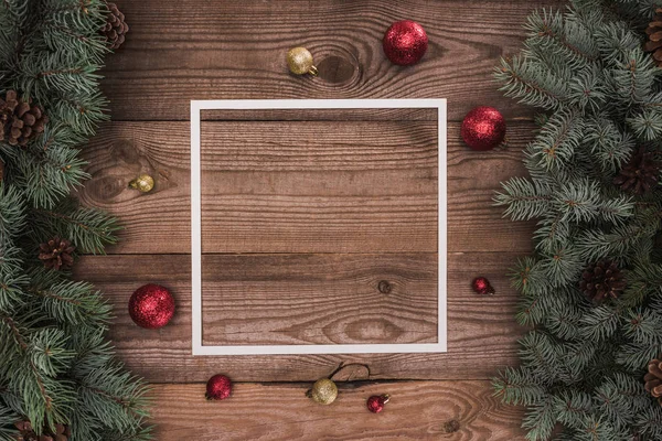 Weißer Rahmen, glänzende rote und goldene Kugeln und Nadelzweige mit Tannenzapfen, weihnachtlicher Hintergrund — Stockfoto