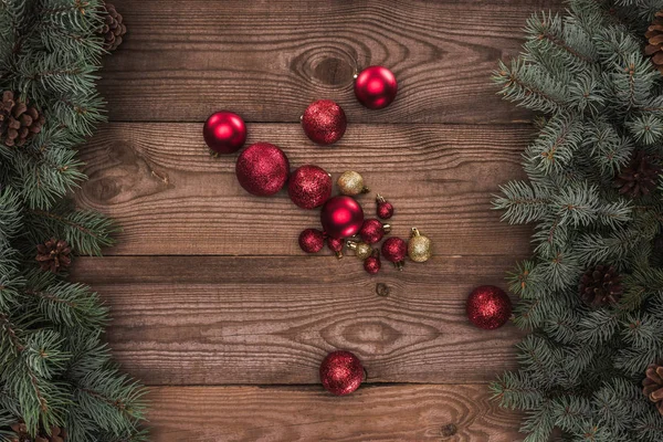 Vista superior de brillantes bolas rojas y doradas y ramas de coníferas con conos de pino, fondo de Navidad - foto de stock