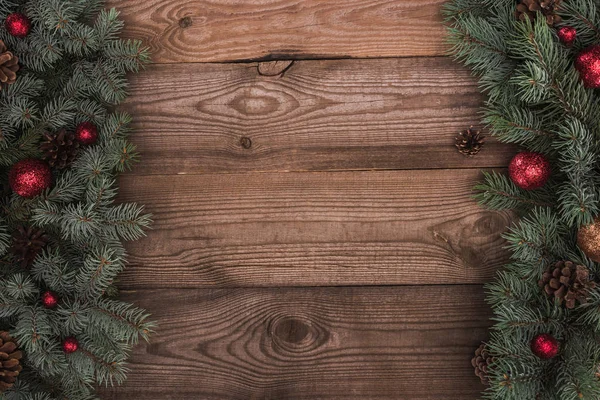 Vista superior de belos galhos de abeto evergreen com bolas brilhantes e cones de pinho no fundo de madeira — Fotografia de Stock