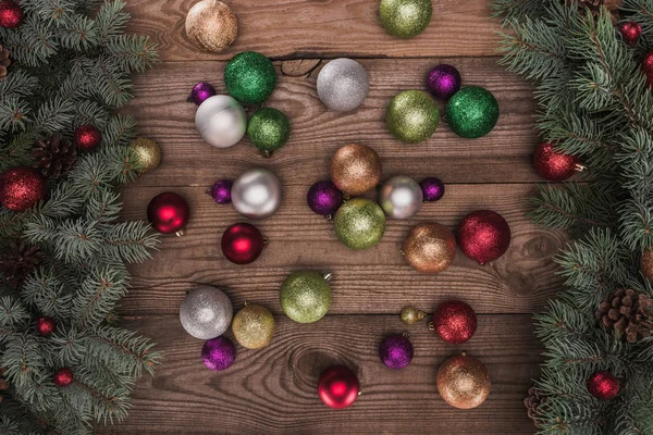 Vista superior de adornos de colores brillantes y ramas de árbol de Navidad sobre fondo de madera - foto de stock