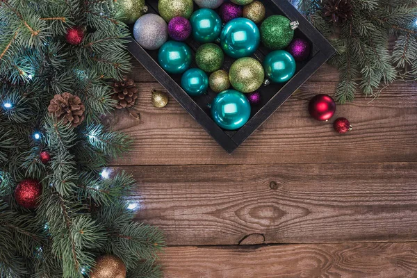 Top view of beautiful shiny baubles and fir twigs with pine cones, christmas background — Stock Photo