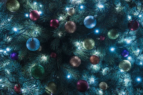 Close-up view of beautiful christmas tree with colorful balls and illuminated garland — Stock Photo