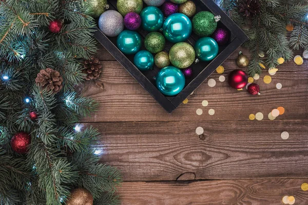 Top view of beautiful colorful shiny baubles and fir twigs on wooden background — Stock Photo