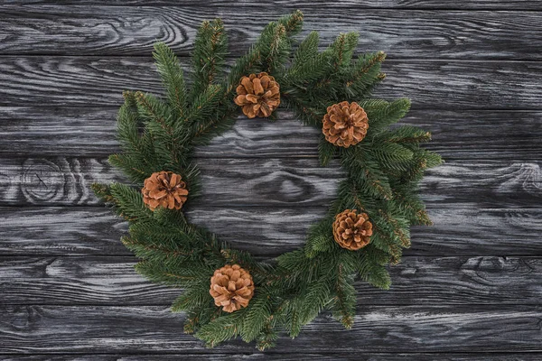 Vista superior de hermosa corona de Navidad con conos de pino sobre fondo de madera - foto de stock