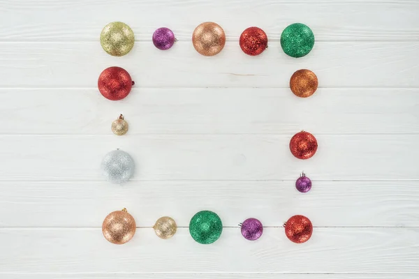 Vue de dessus des boules de Noël colorées brillantes sur fond blanc en bois — Photo de stock