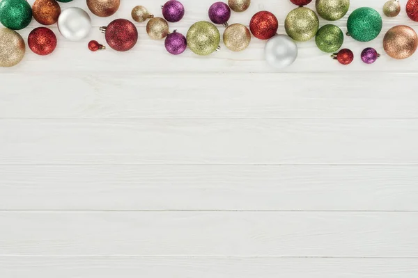 Belles boules de Noël colorées et brillantes sur fond blanc en bois — Photo de stock