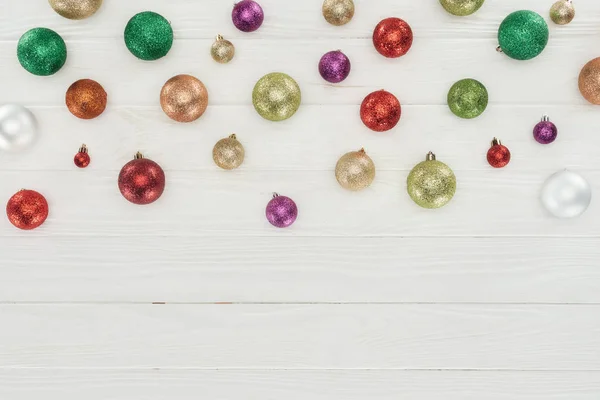 Vue de dessus de belles boules de Noël colorées et brillantes sur fond blanc en bois — Photo de stock