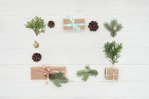 Top view of christmas presents, shiny golden balls, pine cones and coniferous twigs on wooden background — Stock Photo