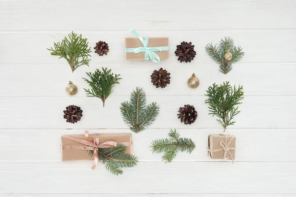 Vue de dessus des cadeaux de Noël, branches de conifères persistantes et cônes de pin sur la surface en bois — Photo de stock