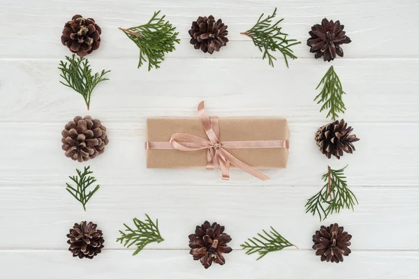 Top view of christmas present and beautiful evergreen coniferous twigs with pine cones — Stock Photo