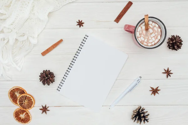 Flache Liege mit blankem Notizbuch und Tasse heißer Schokolade, Marshmallows und Zimtstangen auf Holztisch — Stockfoto