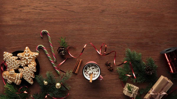 Flat lay com xícara de chocolate quente com marshmallows, paus de canela e decorações de Natal em fundo de madeira — Fotografia de Stock