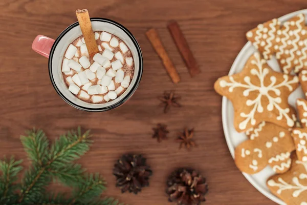 Vue du dessus de la tasse avec chocolat chaud et guimauves, bâtonnets de cannelle et biscuits au pain d'épice — Photo de stock