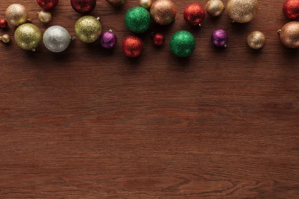 Top view of beautiful shiny colorful baubles on wooden surface, christmas background — Stock Photo