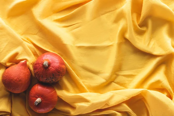 Top view of autumnal three pumpkins on yellow tablecloth — Stock Photo