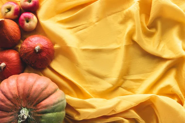 Top view of autumnal pumpkins and apples on yellow tablecloth — Stock Photo