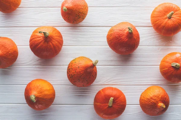 Ansicht von verstreuten orangefarbenen Kürbissen auf hölzerner Tischplatte — Stockfoto