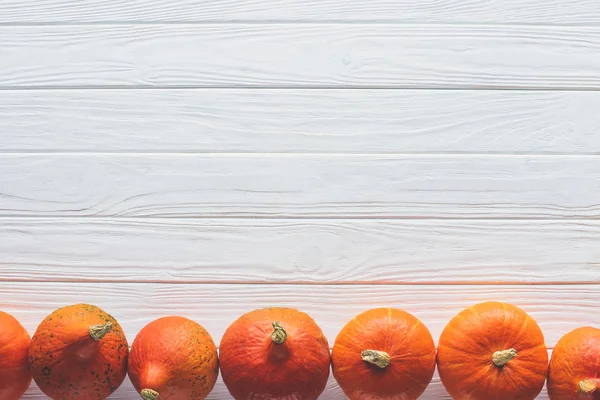 Vista superior de la fila de calabazas maduras de color naranja en el lado de la mesa - foto de stock