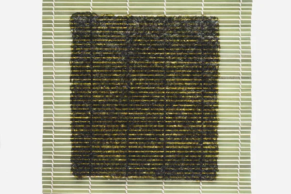 Верхний вид листа нори на рулон салфетки бамбука изолирован на белом — стоковое фото