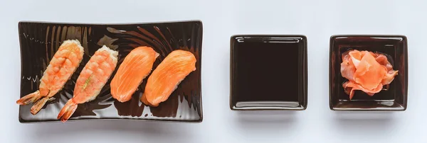Sushi gourmet con salmón y camarones, jengibre y salsa de soja aislados en blanco - foto de stock
