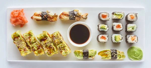 Vista de cerca del delicioso conjunto de sushi con jengibre, wasabi y salsa de soja aislados en blanco - foto de stock