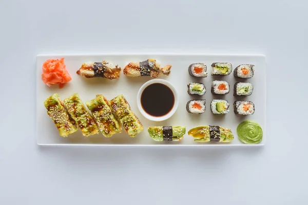 Top view of delicious sushi set with ginger, wasabi and soy sauce isolated on white — Stock Photo