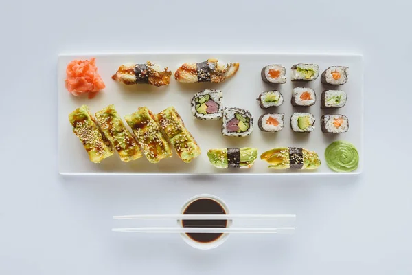 Draufsicht auf Gourmet-Sushi-Set mit Ingwer, Wasabi, Sojasauce und Essstäbchen isoliert auf weiß — Stockfoto