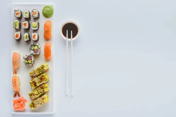 Delicioso conjunto de sushi e molho de soja na tigela com pauzinhos isolados no fundo branco — Fotografia de Stock