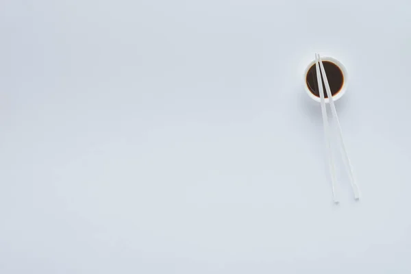 Вид зверху соєвого соусу в мисці і паличках ізольовані на білому тлі — стокове фото