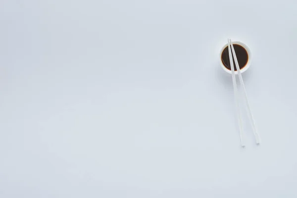 Vue du dessus de la sauce soja dans un bol et des baguettes isolées sur fond blanc — Photo de stock