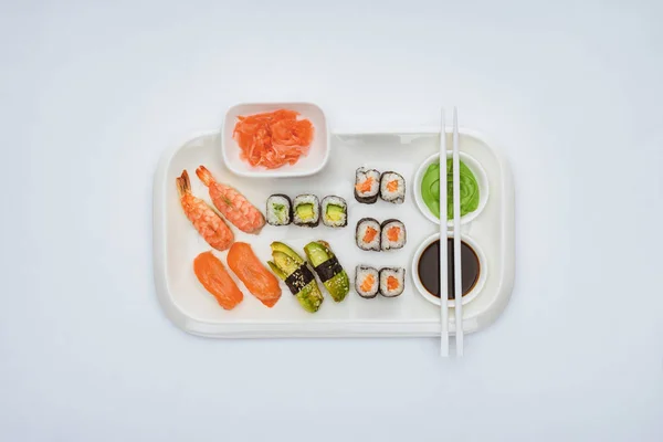 Vista superior del delicioso conjunto de sushi con palillos aislados en blanco - foto de stock