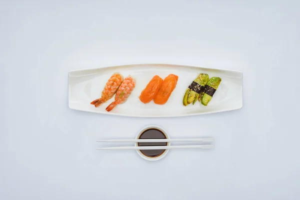 Vista superior de sushi gourmet, molho de soja e pauzinhos isolados em branco — Fotografia de Stock